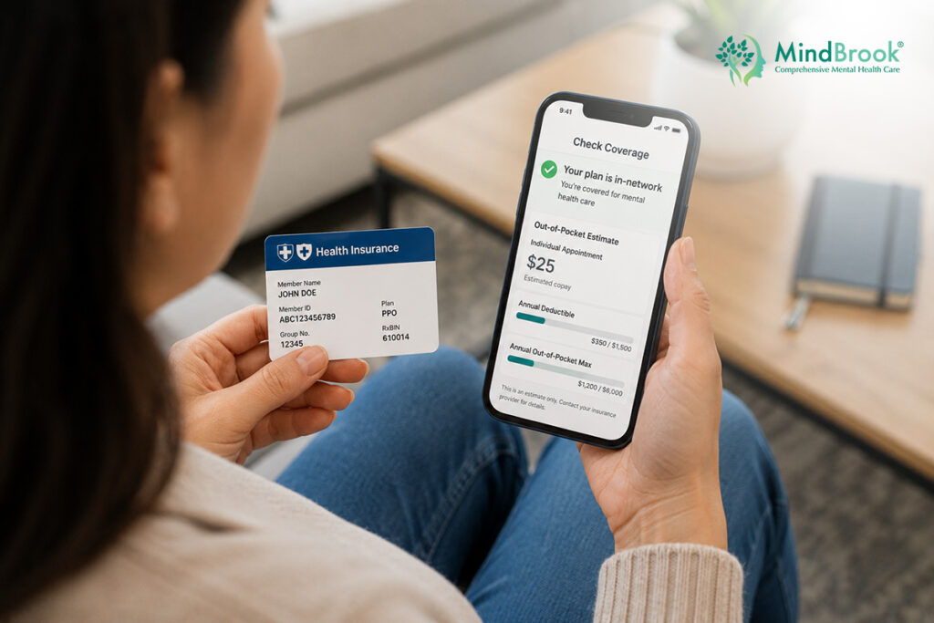 Woman checking mental health insurance coverage on phone while holding insurance card — MindBrook Psychiatry, Tampa FL